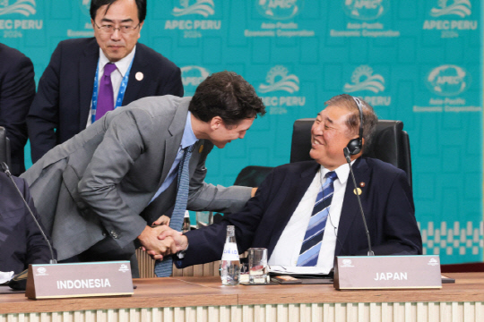 이시바 시게루(오른쪽) 일본 총리가 페루 리마에서 열렸던 APEC정상회의 때 쥐스탱 튀르도 캐나다 총리의 악수를 의자에 앉은 채 받고 있다.   [출처=일본총리관저 홈페이지]